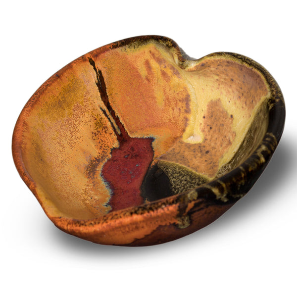 Heart-shaped bowl in earth tones and red. Handmade pottery by Prairie Fire Pottery. Hand made is stoneware clay in the U.S.A. 3/4 view.