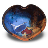 A 5 inch handmade pottery bowl in the shape of a heart. Beautifully glazed in cobalt blue, toasted orange, and red by Prairie Fire Pottery.  Overhead view.