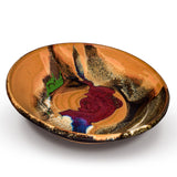 13 inch wheel-thrown stoneware bowl accented with vibrant red, green, and purple-blue colors.  Handmade pottery by Prairie Fire Pottery.  3/4 view.