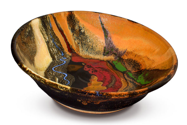 Handmade pottery bowl.  12 inch diamenter.  Earth tone and red colors accented with a ribbon of blue.  Handmade by Prairie Fire Pottery.  3/4 view of the bowl.