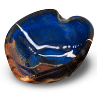 A handmade pottery heart bowl in beautiful cobalt blue colors accented with toasted brown and red.  It is hand made in the U.S.A. by Prairie Fire  Pottery.  3/4 view.