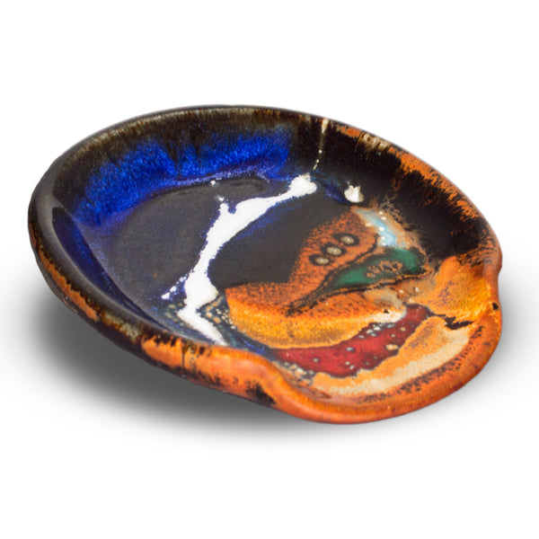 Beautiful handmade pottery spoon rest in cobalt blue and toasted orange colors.  It is handmade pottery by Prairie Fire Pottery.  Hand made in stoneware clay.  3/4 view.