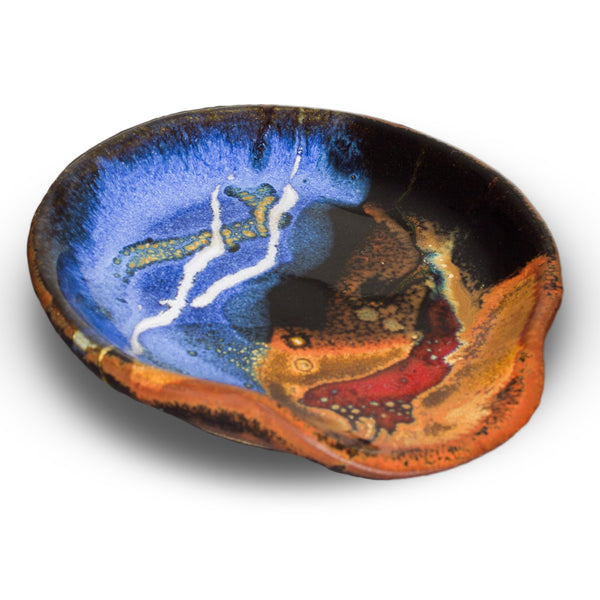 Beautiful milky blue spoon rest accented with toasted brown and red.  Hand made in stoneware clay and high-fired to 2400°.  It is handmade pottery from Prairie Fire Pottery.  3/4 view.