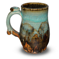 This is a pretty 14 ounce stoneware mug from Prairie Fire Potterey.  It is high-fired to 2400° to achieve the  beautiful blending of the turquoise-brown colors.  Left side view.