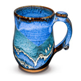 18 ounce wheel-thrown stoneware mug in a blend of cobalt blues and black.  This is handmade pottery by Prairie Fire Pottery.  You're looking at the right side view of the mug.