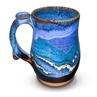 18 ounce wheel-thrown stoneware mug in a blend of cobalt blues and black.  This is handmade pottery by Prairie Fire Pottery.  You're looking at the left side view of the mug.