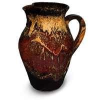 56 ounce wheel-thrown pitcher in earth tone colors over black.  Handmade pottery crafted in stoneware clay by Prairie Fire Pottery.  Right side view.