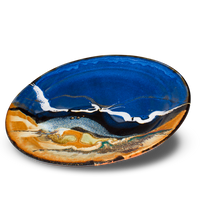 Handmade pottery platter. 14-inch diameter. Beautifully glazed in cobalt blue, toasted orange, and black. Hand made in stoneware clay by Prairie Fire Pottery. 3/4 table top view.