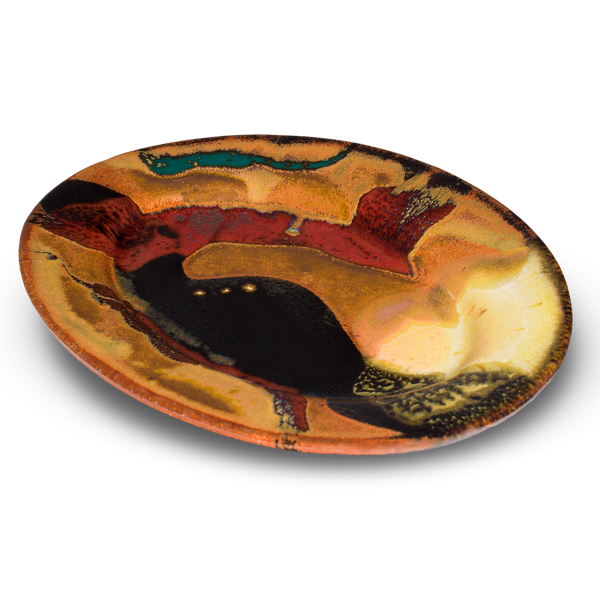 This 9-inch stoneware oval plate is glazed in earth tone colors accented with red and black.  It is handmade pottery fired to 2400° by Prairie Fire Pottery.  Hand made in the U.S.A.  3/4 table top view.