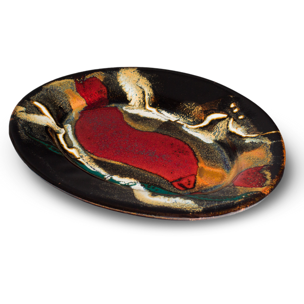 Oval plate with a 9-inch diameter . Handmade pottery by Prairie Fire Pottery. Toasted brown , red, and teal colors against a black background. Table top 3/4 view.