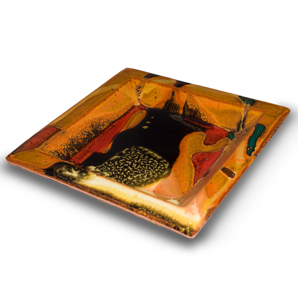 This is handmade pottery crafted into an 8 inch by 8 inch square plate.  It has pretty earth tones colors accented by red.  Handmade pottery by Prairie Fire Pottery.  Made in the U.S.A. from stoneware clay.  This is a 3/4 table top view.