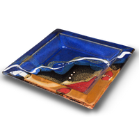 8 inch square plate.  Cobalt blue and toasted brown colors, accented with red.  Handmade pottery from Prairie Fire Pottery.  This is a 3/4 table top view.