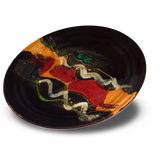 A beautiful blend of colors in this 14 inch platter. Glazed in toasted orange on black with gold, green, and blue accents. Handmade pottery from the studio of Prairie Fire Pottery. Hand made in stoneware clay in the U.S.A.  3/4 table top view.