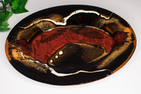Red and toasted orange colors on black. 9 inch oval plate.  Handmade pottery by Prairie Fire Pottery.