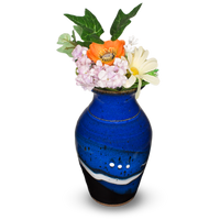 A classic flared-neck vase by Prairie Fire Pottery in a blend of cobalt blues and black. Handmade pottery crafted in stoneware clay. Made in the U.S.A.  View holding a bouquet of flowers.